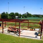 Steel batting cage under construction with red steel framing