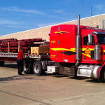 Truck delivering red steel framing for building construction