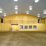 Indoor steel horseback riding arena with wooden wall