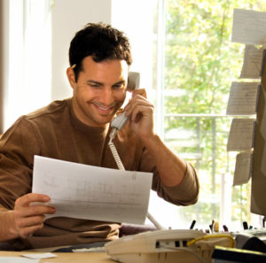 Photo of a smiling man on a phone with a customer service rep.