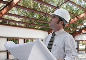 Builder in hard hat examines steel building system.