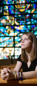 Woman prays in front of a steel glass window in this discussion of steel church buildings