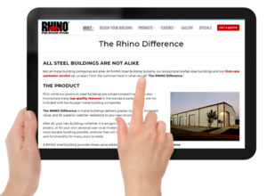Hands holding a digital tablet with The RHINO Difference web page on the screen.