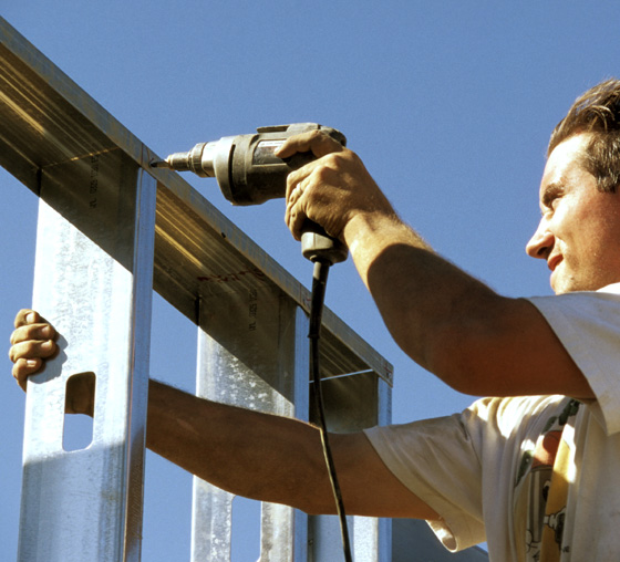 Photo of a man install screws in a light-gauge metal building
