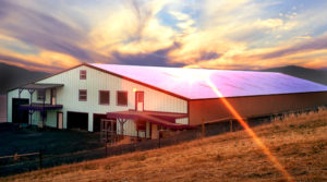 Photo of a huge RHINO barn and stables at sunset.