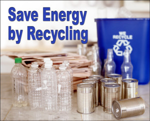 Piles of newspapers, empty plastic drink bottles, and steel cans with the headline: "Save Energy by Recycling"