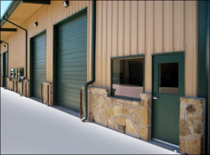 Attractive tan metal building with forest green and stone trim