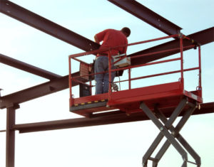 Man on a scissor lift assembling a RHINO steel building.