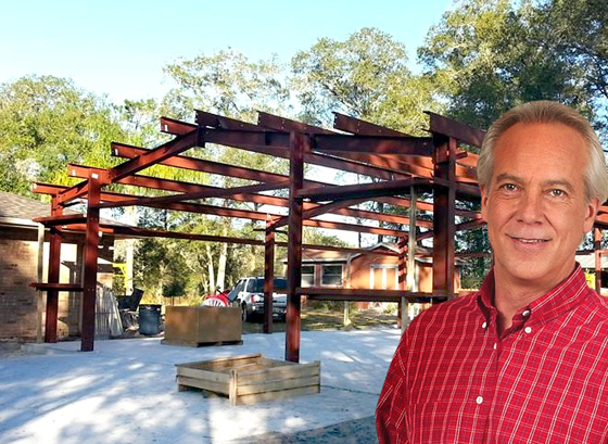 Photo of man proudly standing before his new RHINO garage under construction.