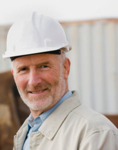 Photo of a builder wearing a hard hat in front of a completed metal building.