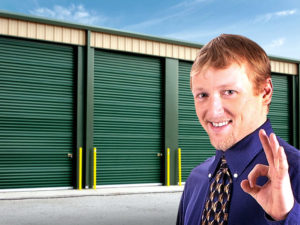 Happy business owner stands before steel building units at his self-storage facility.