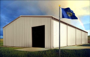 Large beige and tan-trimmed metal building under rainbow with Nebraska flag flying