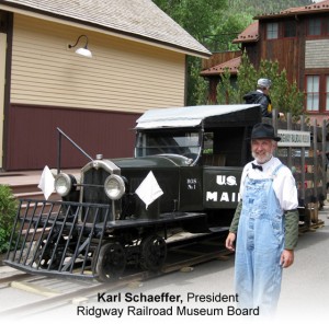 Karl Schaeffer stand by vintage railroad mail car at the Ridgway Railroad Museum in Colorado