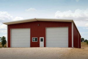 Photo of a red metal barn with white trim and two large overhead doors.