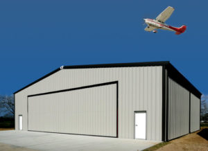 Photo of attractive RHINO metal airplane hangar with plane flying over it.