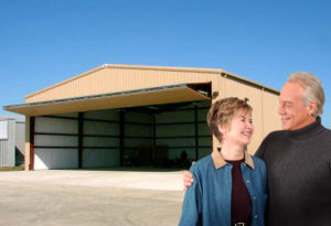 Photo of one of RHINO's metal hangars with proud couple standing in front of it.