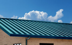 Photo of a bricked metal building with a blue-green metal roof panels.