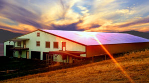 The sun sets over a huge rural metal building in Texas.