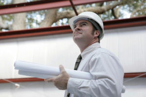 Photo of a builder overseeing the erection of his prefab steel building.