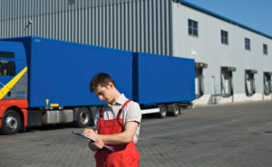 Photo of a warehouse worker and truck before a two-story metal building warehouse.