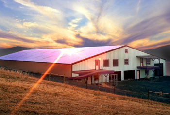 Photo of a huge covered horse riding arena at sunset.
