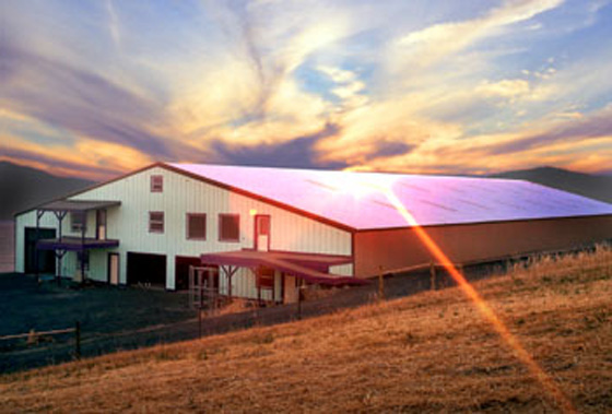 Photo of a large steel riding arena at sunset.