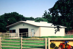 Photo of a RHINO metal barn with a rail fence around it.