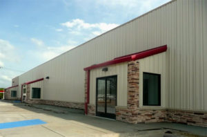 Photo of an attractive industrial metal building with pop-pot entryways trimmed in ledge stone.
