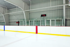 Photo of the inside of a hockey rink in a metal building.