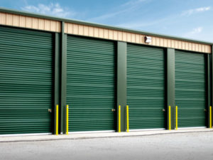 Tan self-storage units with forest green doors and trim.