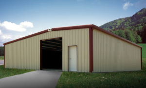 Tan RHINO metal farm building with a dark red trim and an open doorway.